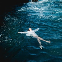 a woman in a white dress floating in the ocean