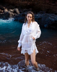 a woman in a white dress standing in the ocean